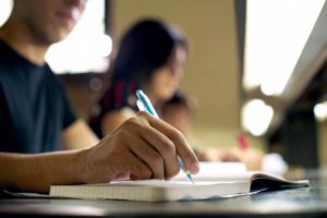 A person writing in a notebook during a class.