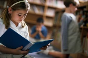 Young girl reading a book in a library.