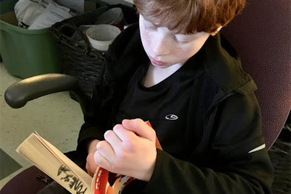 Little Boy Looking Focused While Reading A Book